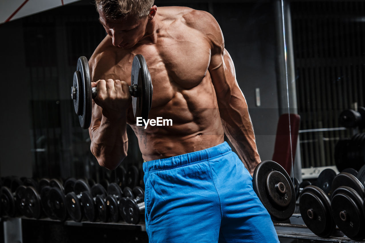 Shirtless man exercising in gym