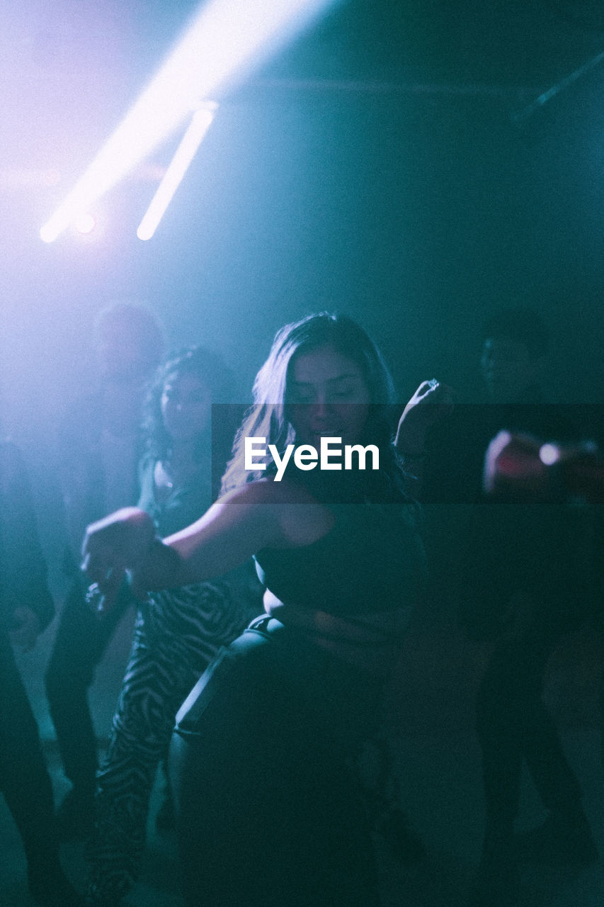 Young woman dancing against friends in background at nightclub