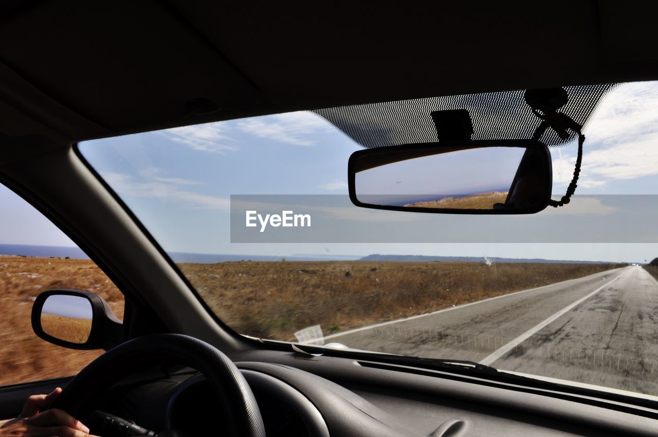 Close-up of side-view mirror seen through car window