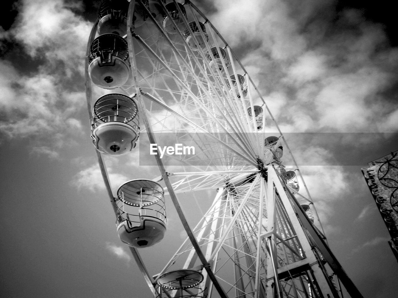 Low angle view of ferris wheel against cloudy sky