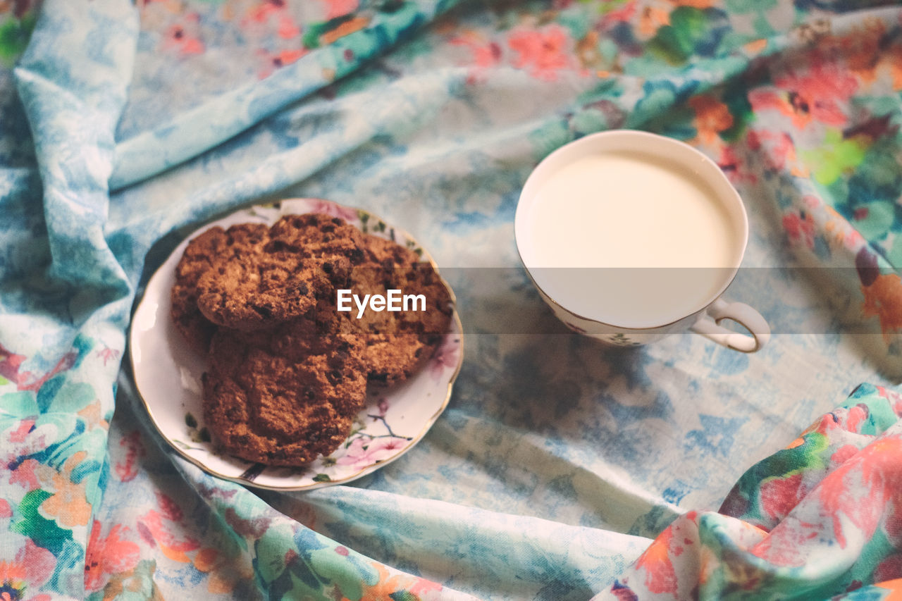 High angle view of cookies in plate with milk on table