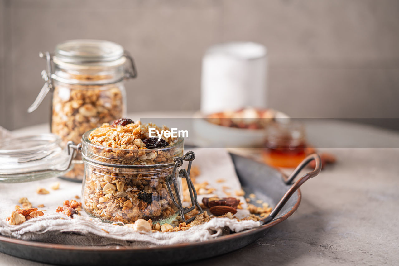 food and drink, food, meal, healthy eating, jar, fruit, breakfast, wellbeing, eating utensil, granola, dish, sweet food, freshness, kitchen utensil, produce, nut, nut - food, studio shot, no people, snack, seed, baked, indoors, dried food, spoon, dried fruit, sweet, crockery, wood, table, container, dairy, plate, dessert, oats - food, almond, muesli, rustic