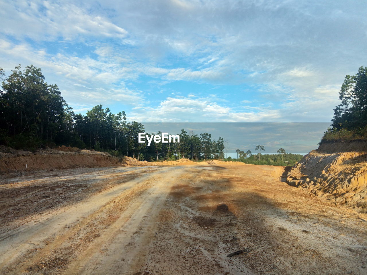 Dirt road passing through landscape against sky