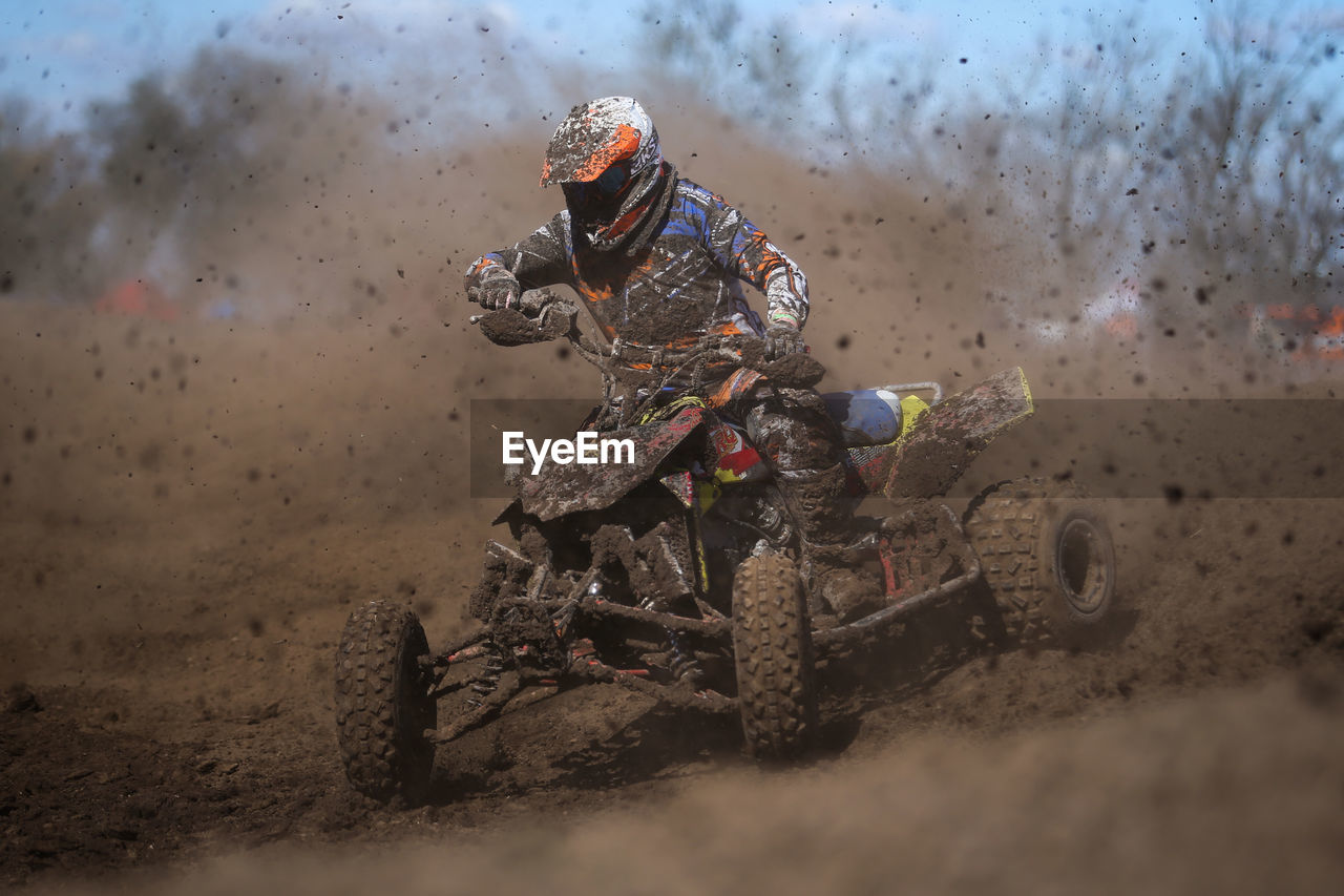 Racer riding quadbike in dirt during race