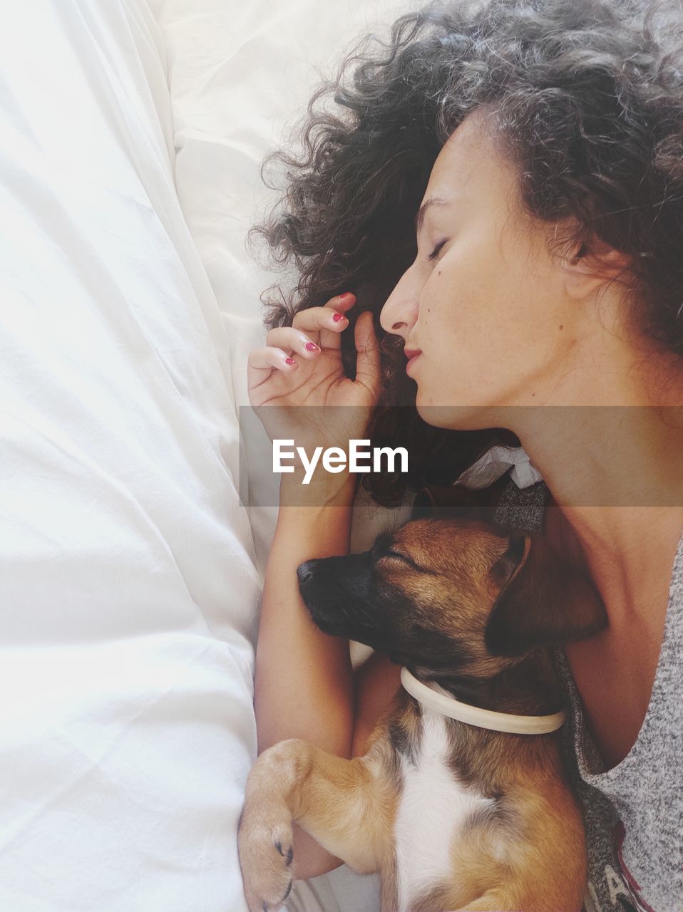 Midsection of woman sleeping with her dog on bed