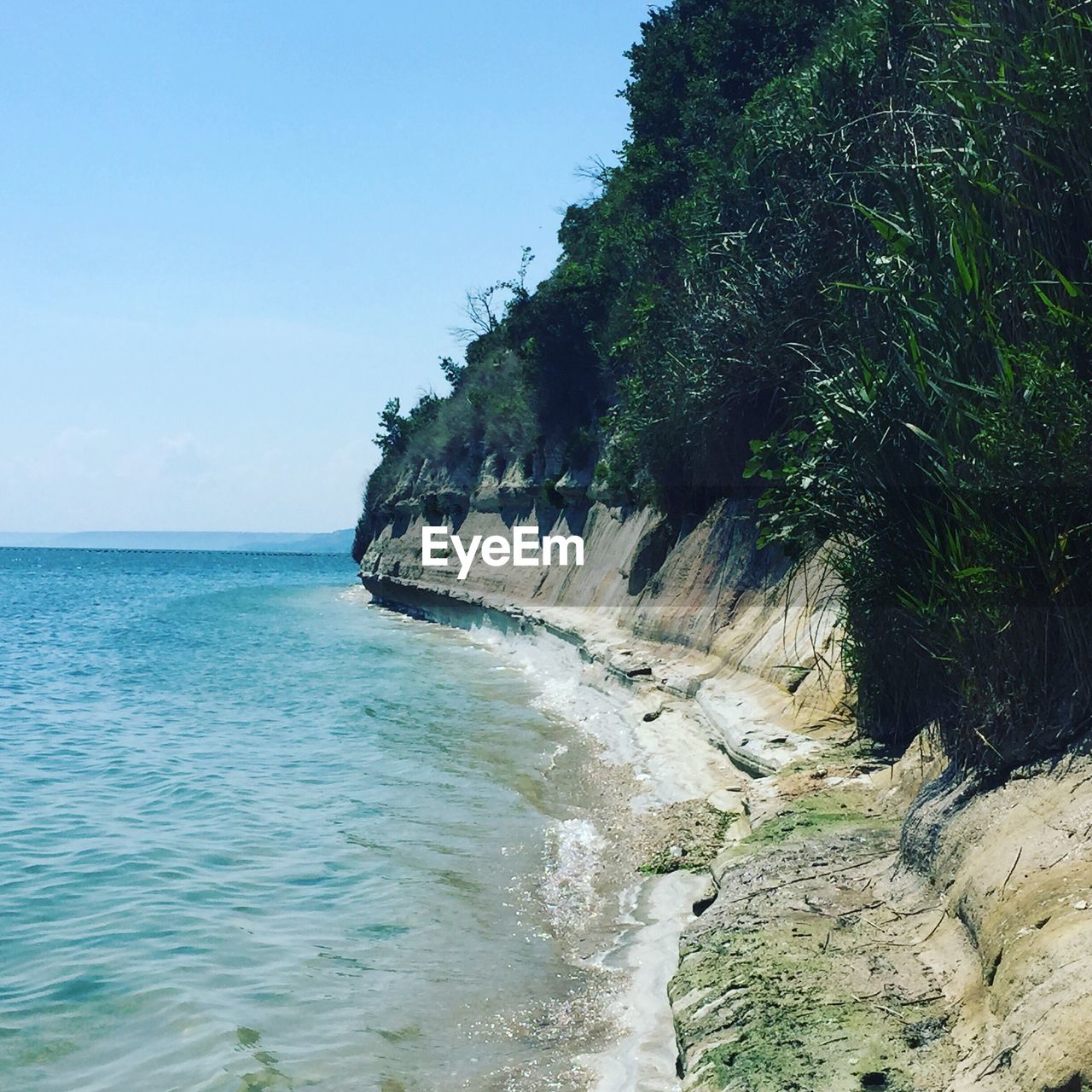 Rock formation by sea against blue sky