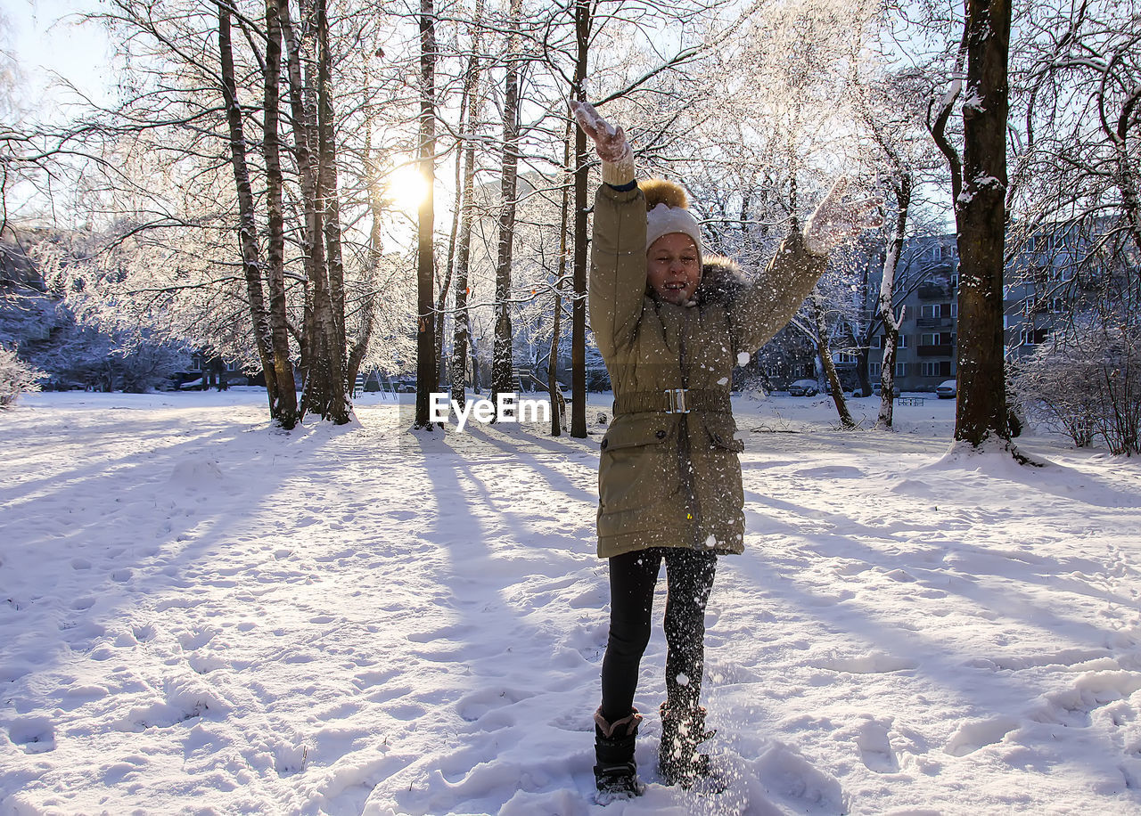 Full length of girl throwing snow in air outdoors