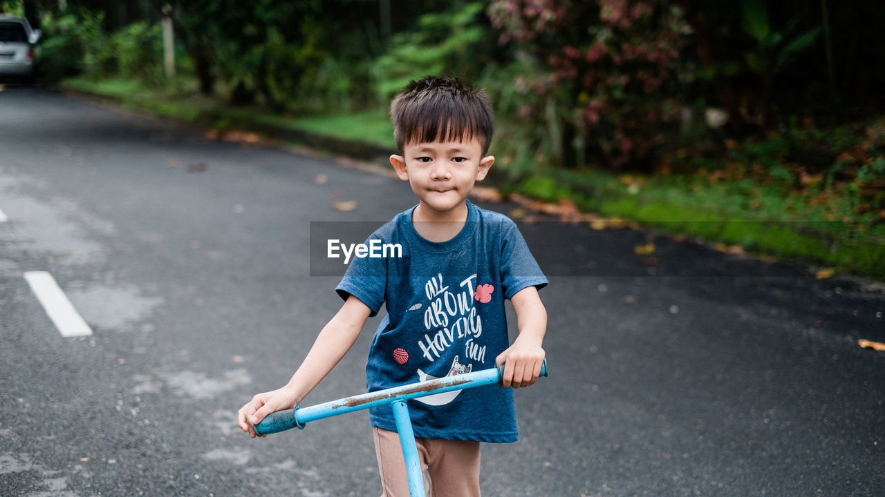 Boy riding push scooter on road