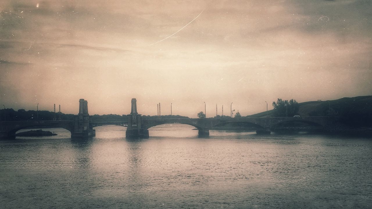 Bridge over river against cloudy sky