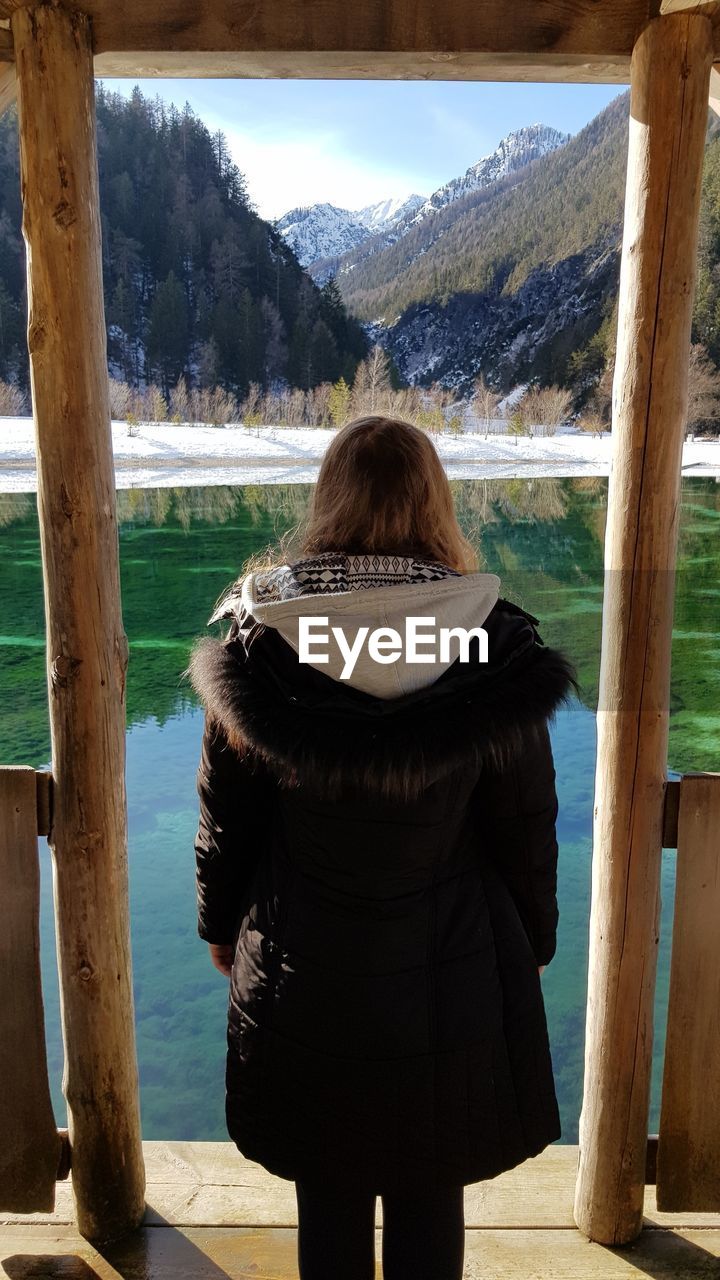 Rear view of woman looking at lake against mountain