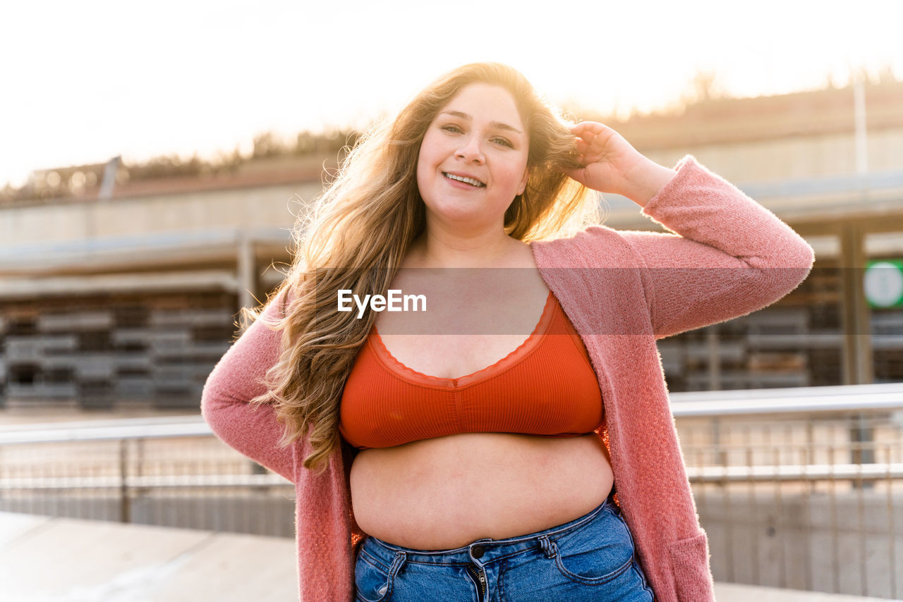 Portrait of young woman standing against building