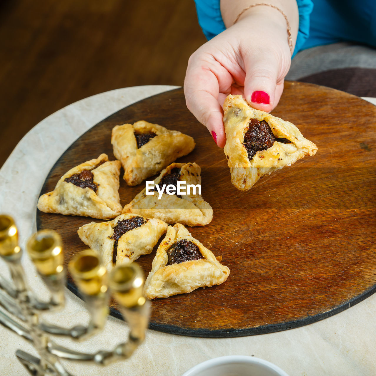 Women's hands laying gomentashi cookies on a wooden board for the festive table for purim.