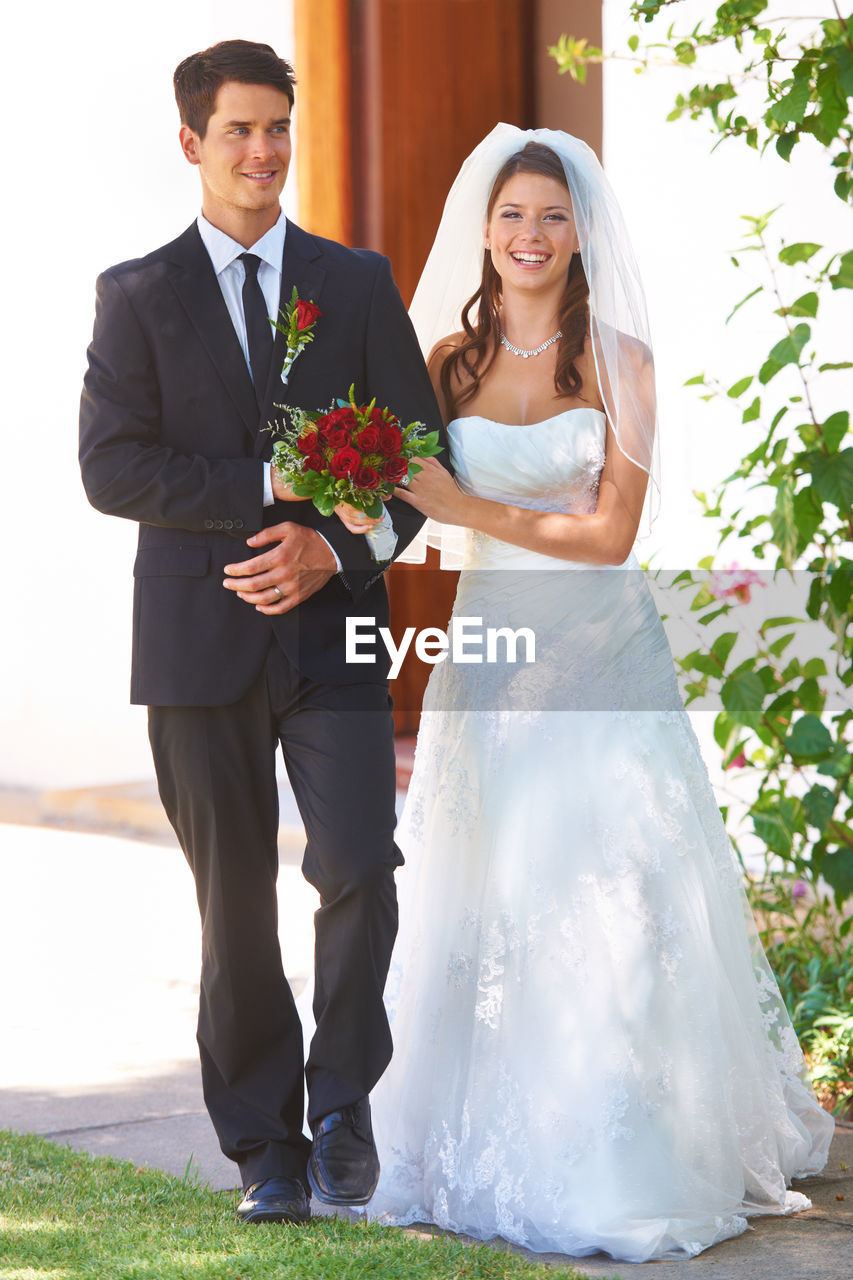adult, wedding, event, bride, celebration, newlywed, women, married, two people, love, emotion, wedding dress, men, life events, togetherness, happiness, positive emotion, young adult, plant, smiling, flower, female, formal wear, bouquet, flower arrangement, ceremony, clothing, nature, romance, gown, standing, wedding ceremony, flowering plant, beginnings, bridal clothing, full length, cheerful, portrait, bonding, veil, tuxedo, fashion, person, outdoors, looking at camera, dedication, business, affectionate, elegance, holding, tradition, day, dress, lifestyles, fashion accessory