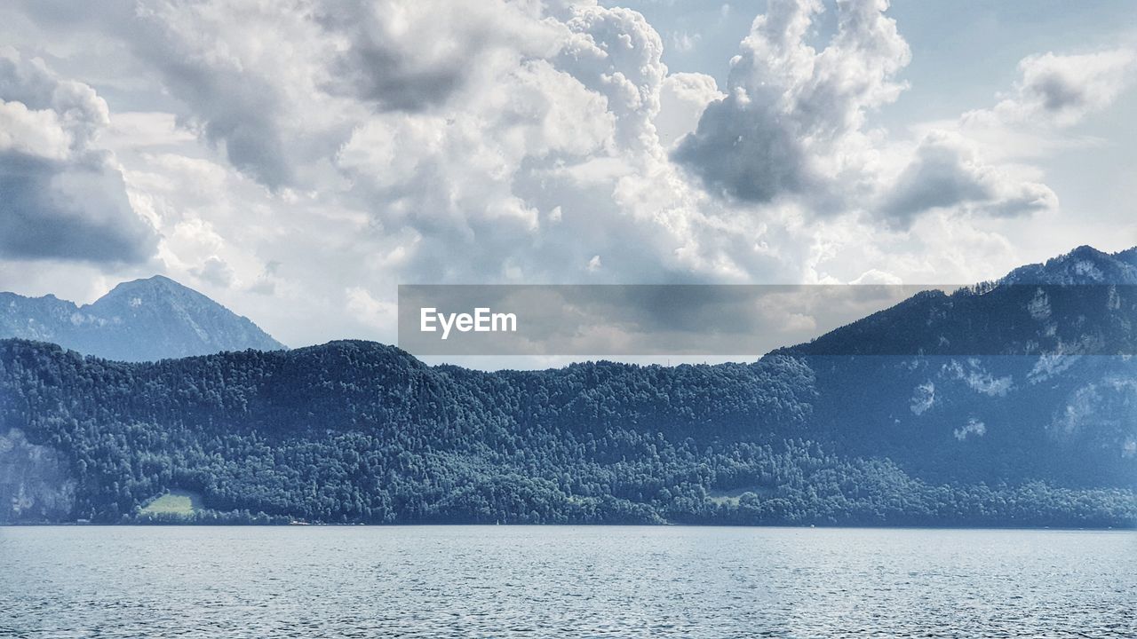 Scenic view of lake by mountains against sky