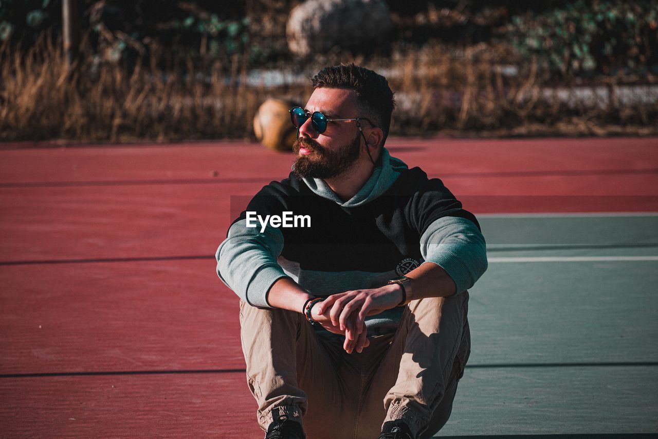 Young man looking away while sitting on sunglasses