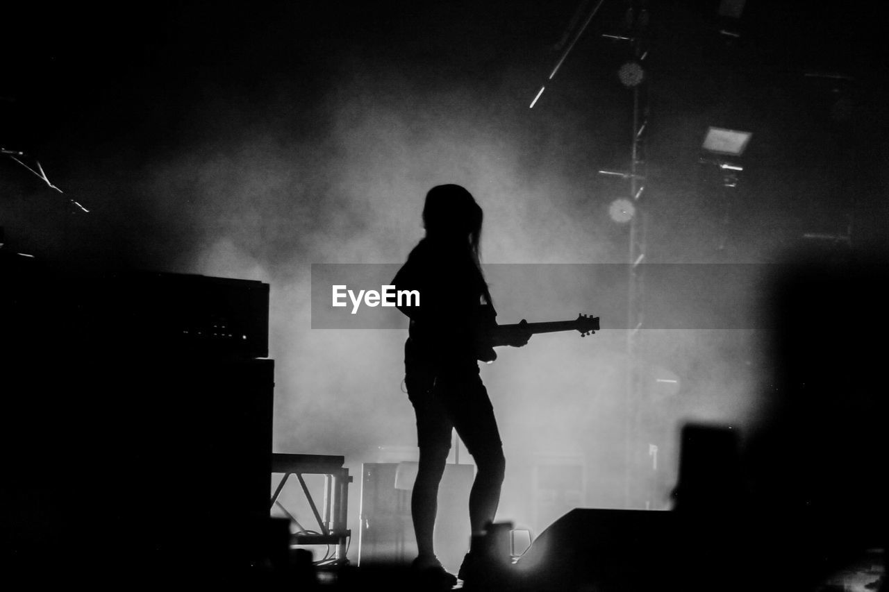 Silhouette person playing guitar at music concert