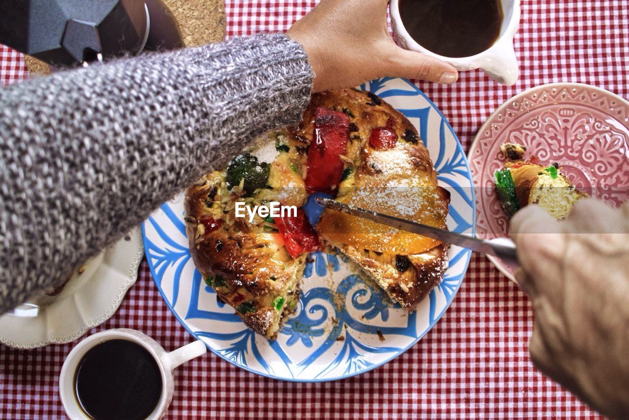 Cropped hand of person cutting bolo rei on table during christmas