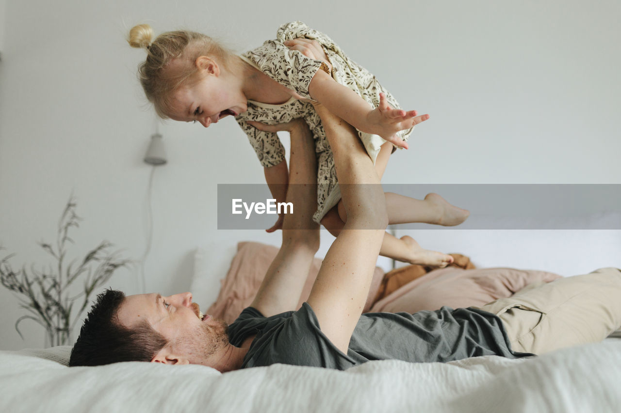 Father playing with daughter on bed