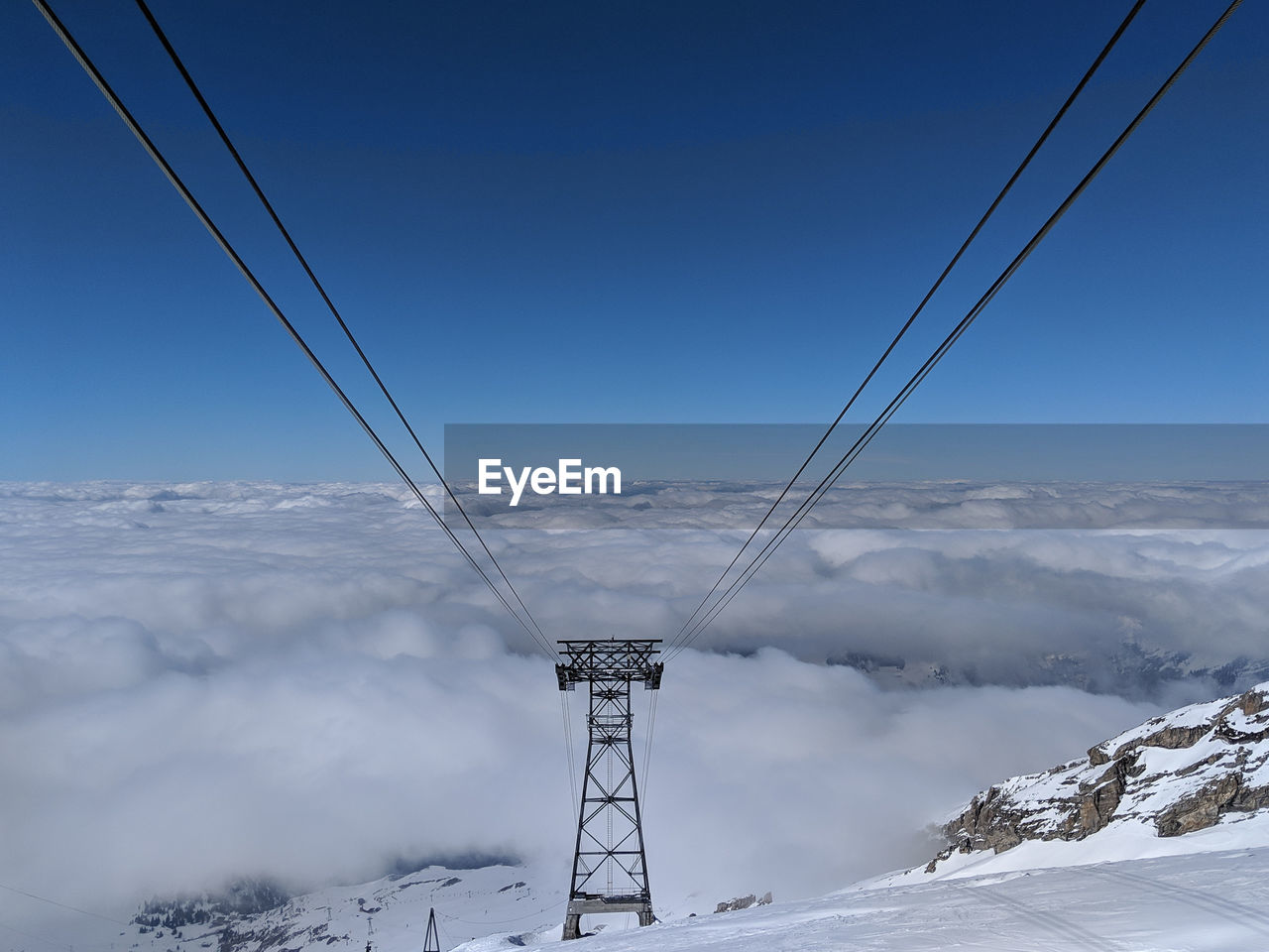 Electricity pylon on snow covered mountain against sky