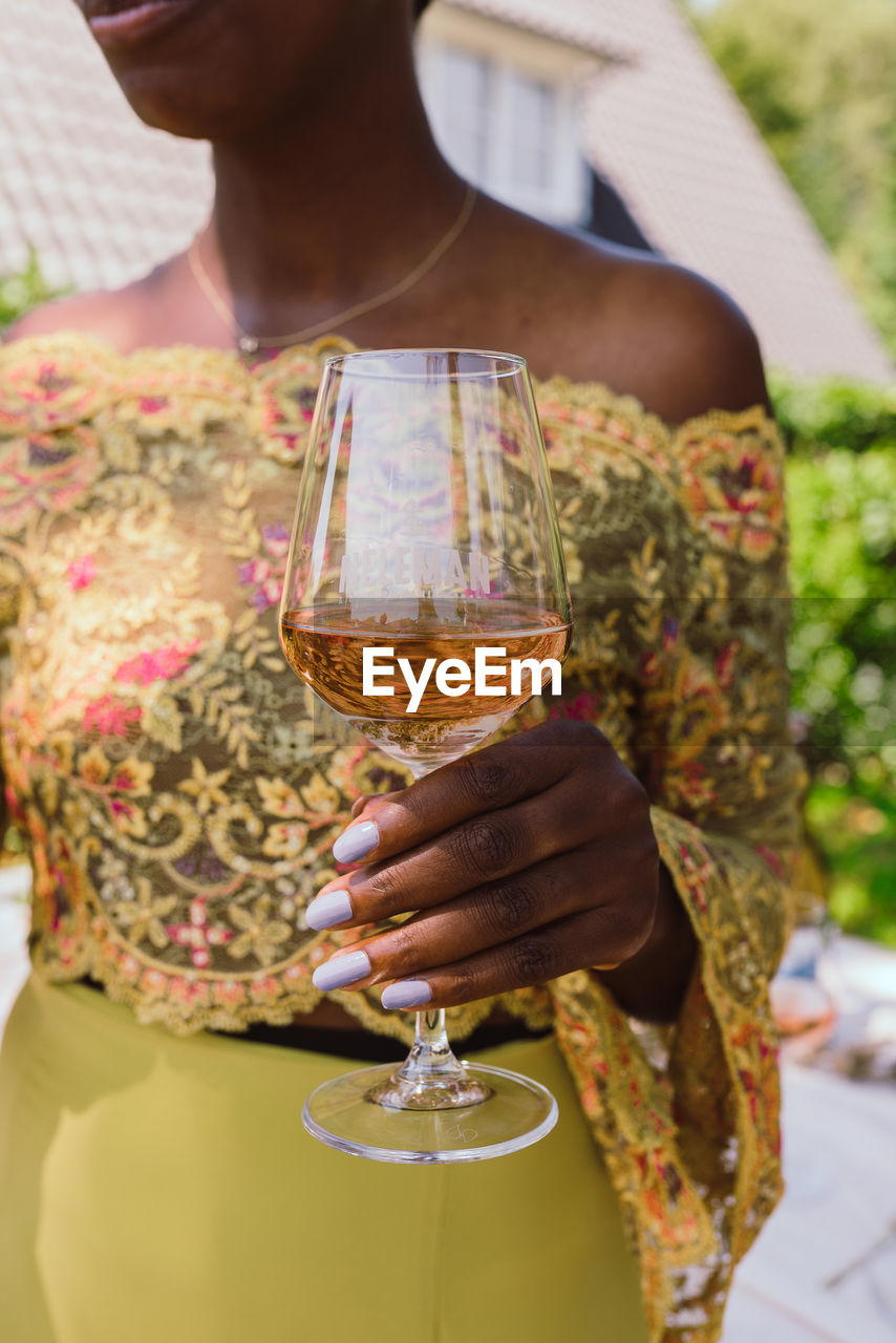 MIDSECTION OF WOMAN DRINKING GLASS WITH WINE