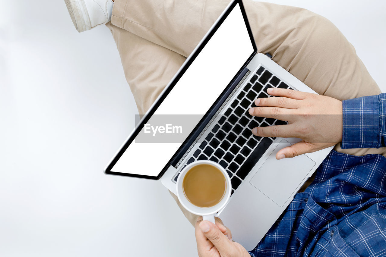 MAN HOLDING COFFEE CUP WITH LAPTOP