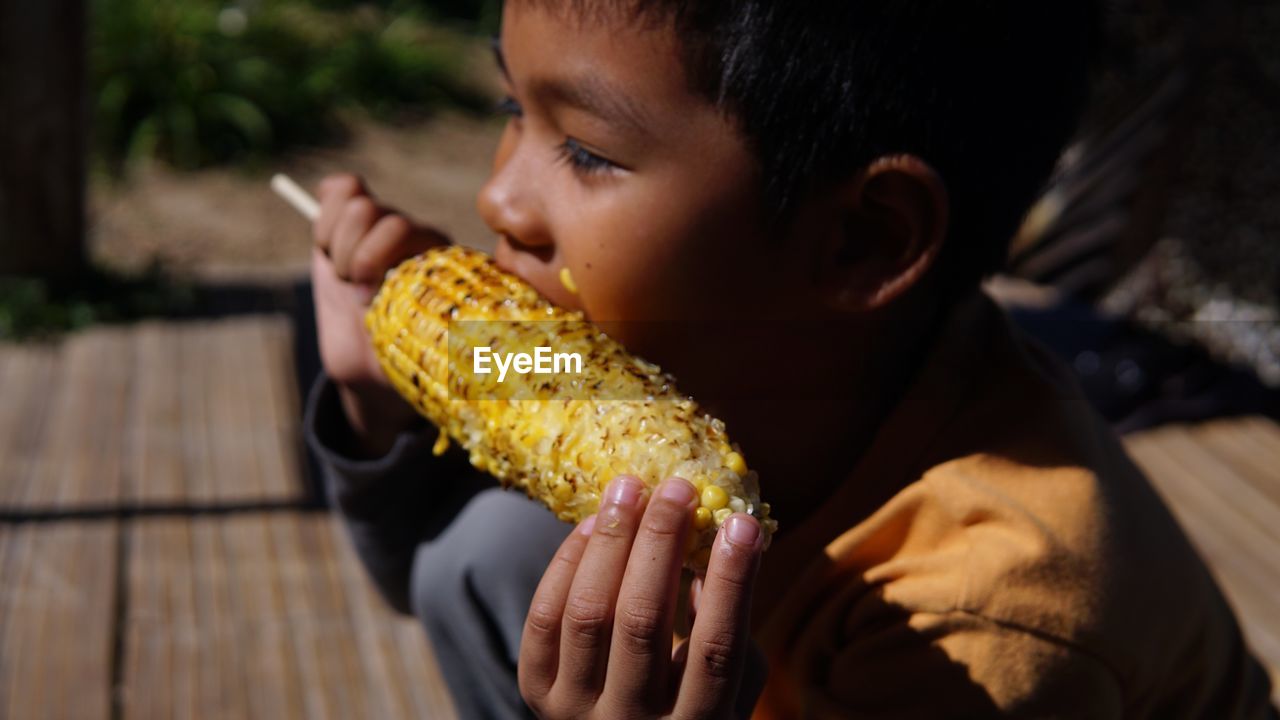 Close-up of boy eating corn while sitting outdoors