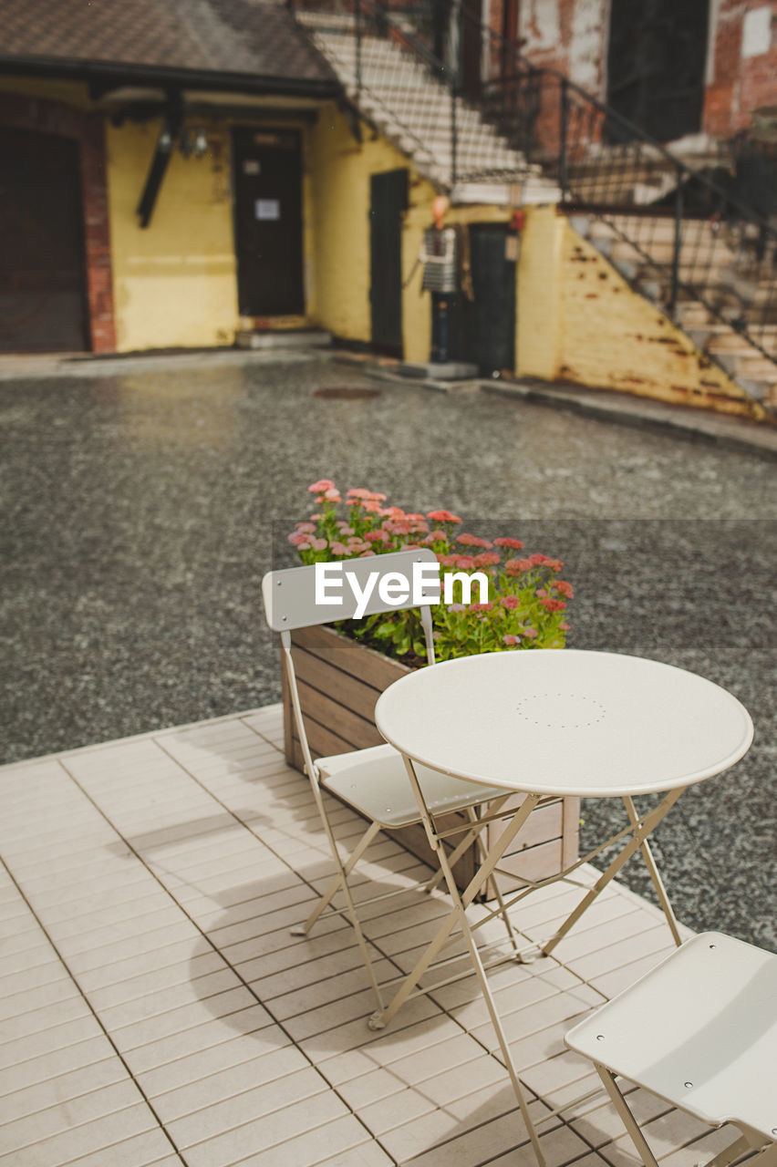 Stylish cafe with decor of green living plants, white table and chairs without visitors