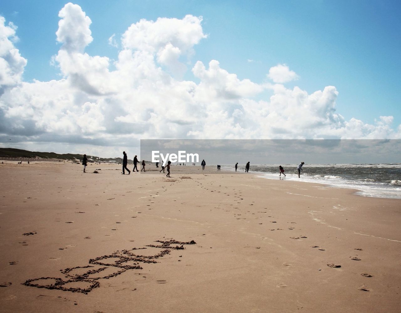 View of beach with text engraved on sand against cloudy sky