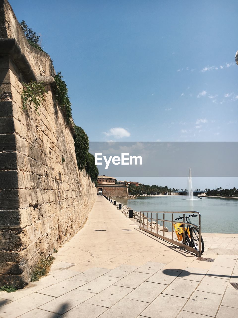 Footpath by sea in city against sky