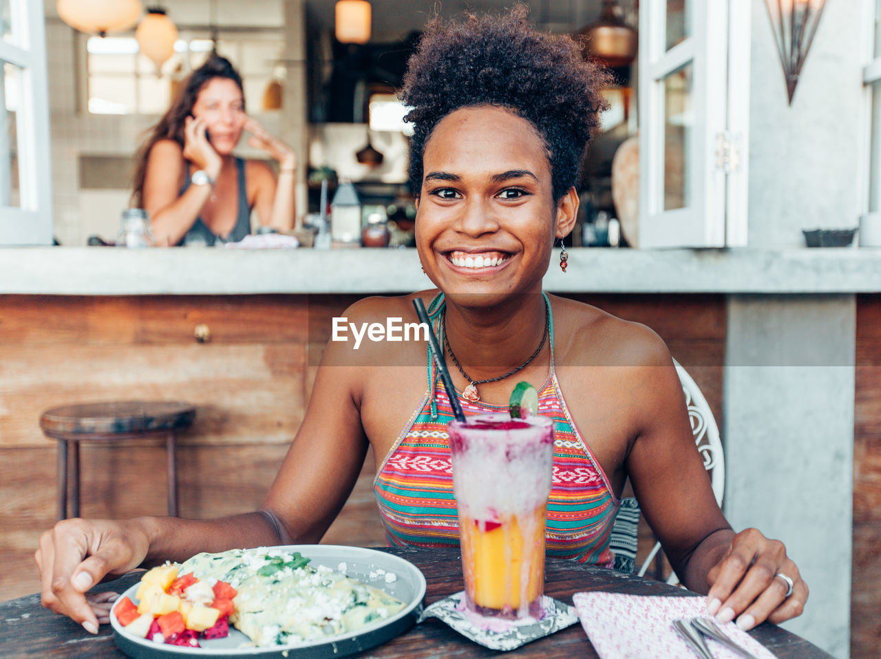 Portrait of smiling young woman having food and drink in restaurant