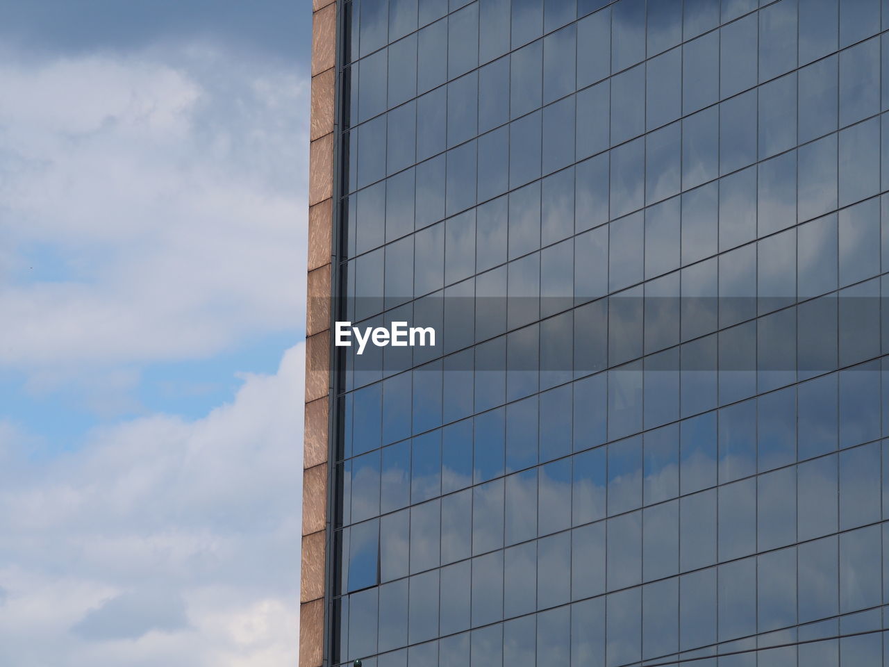 Low angle view of clouds reflecting on glass building