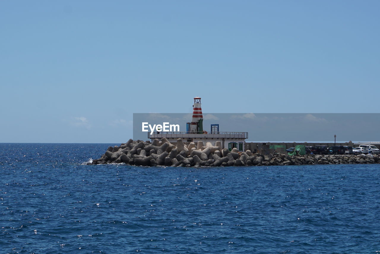 Lighthouse by sea against sky