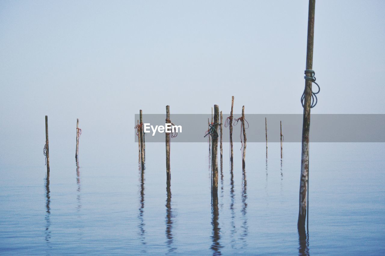 WOODEN POST IN SEA AGAINST SKY