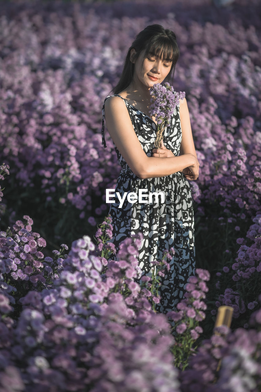 Woman standing amidst purple flowering plants