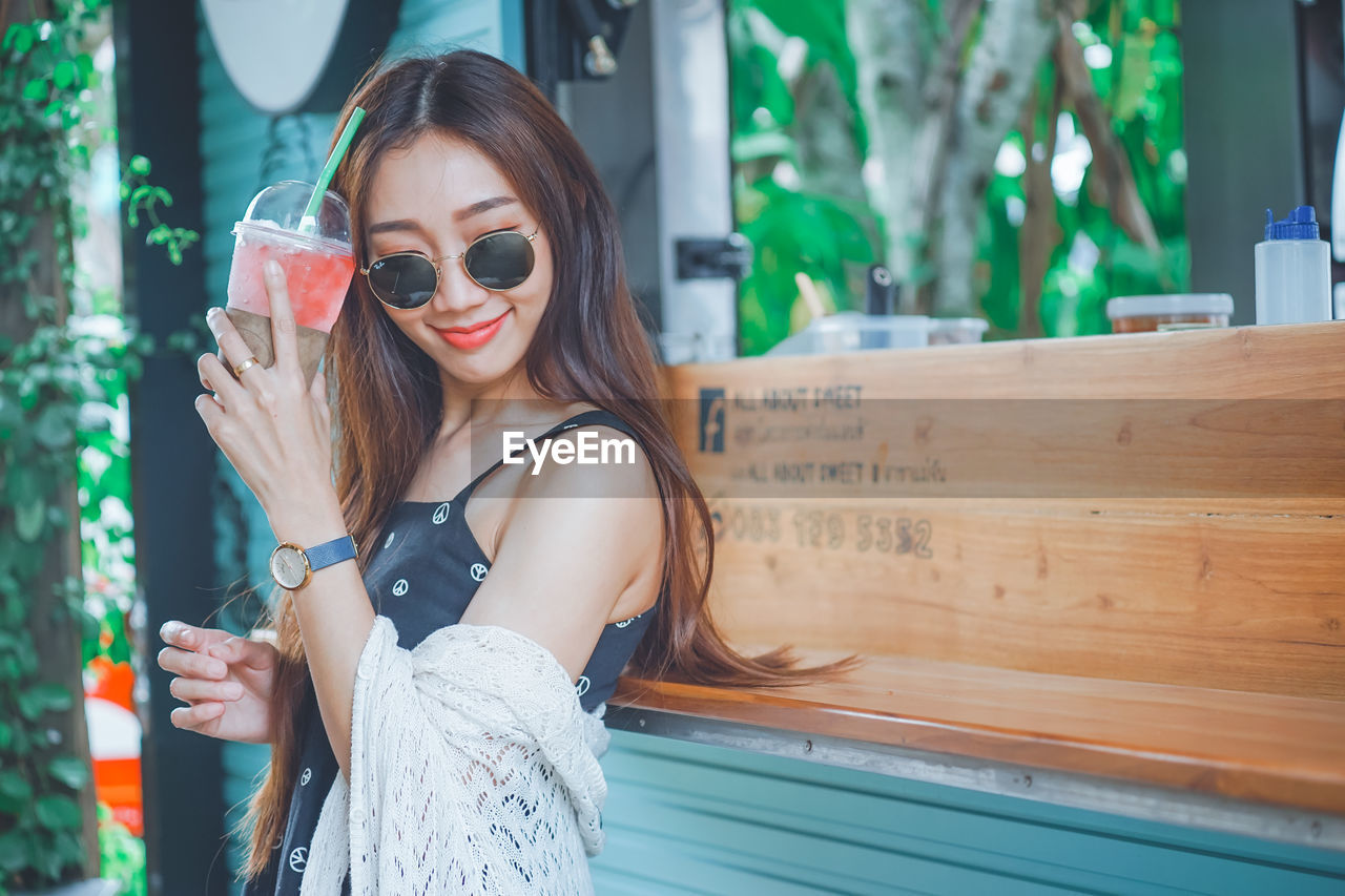 Young woman holding drink standing outdoors