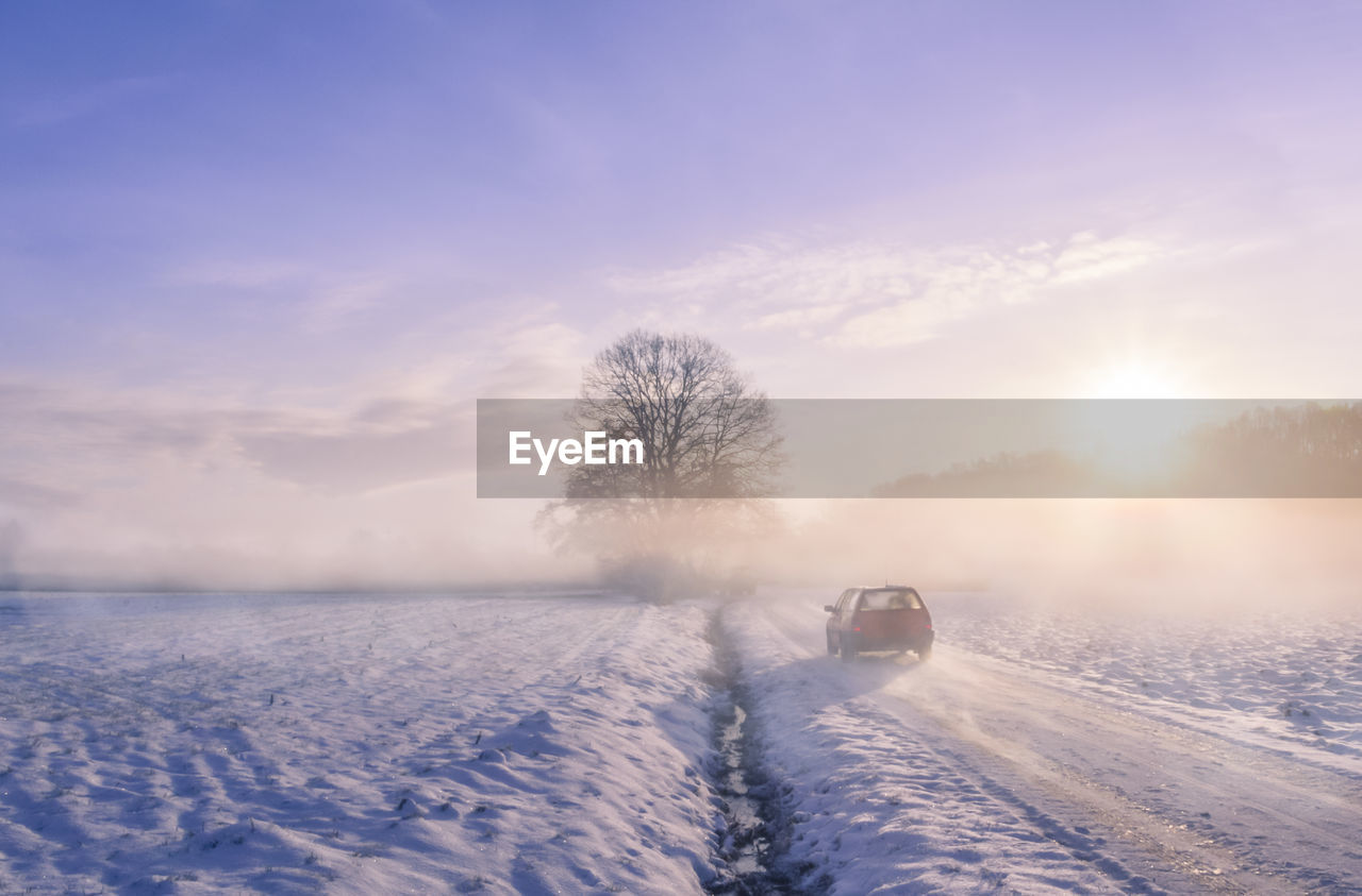 Scenic view of snow covered road  at sunrise