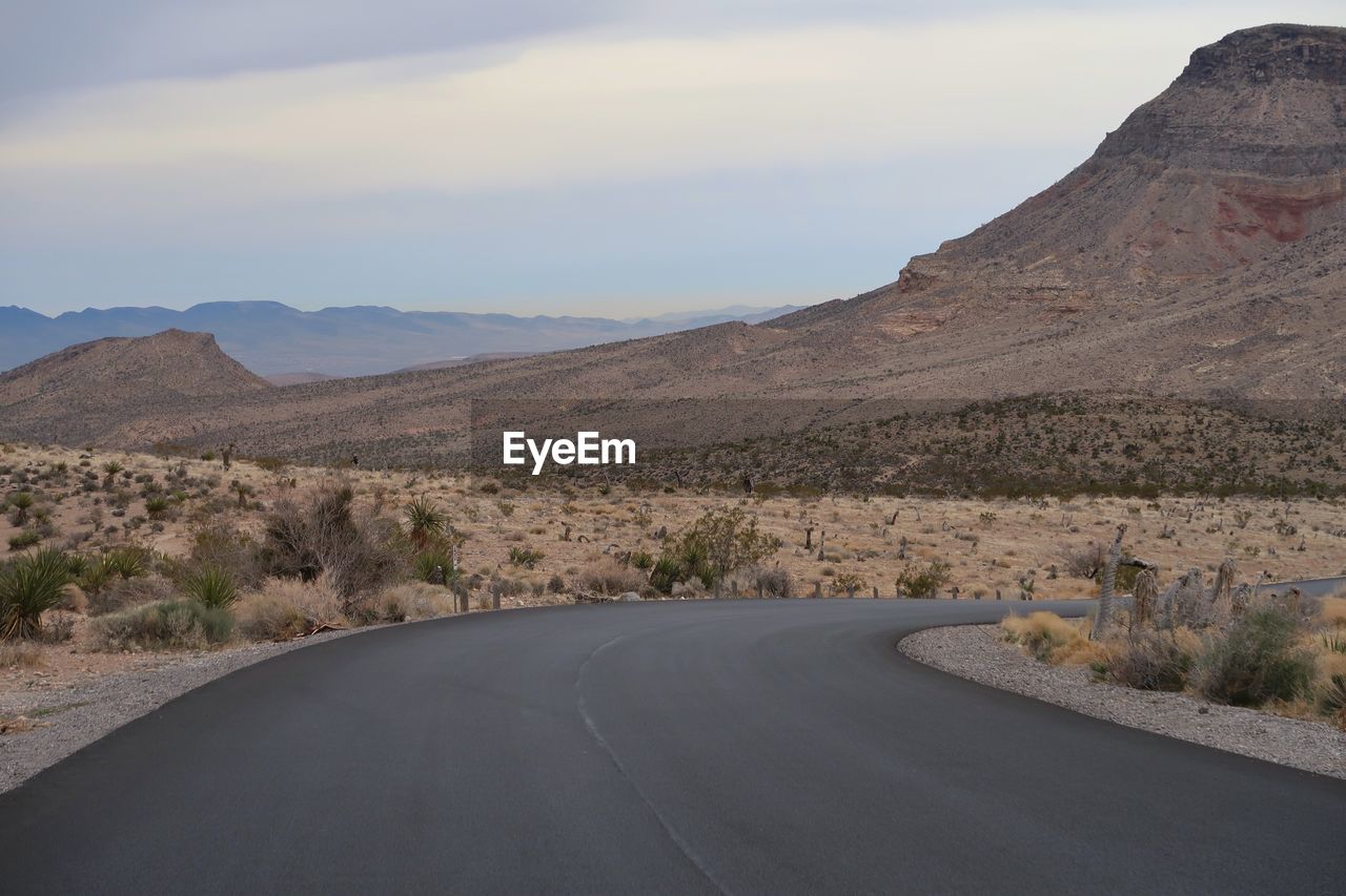 Road by mountains against sky