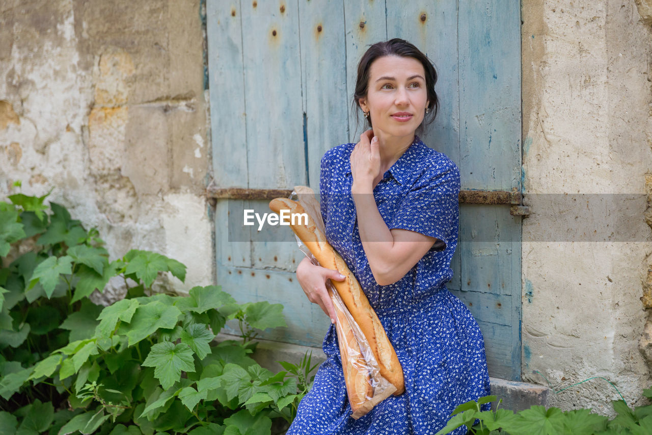Young woman standing with french baguettes in the countryside