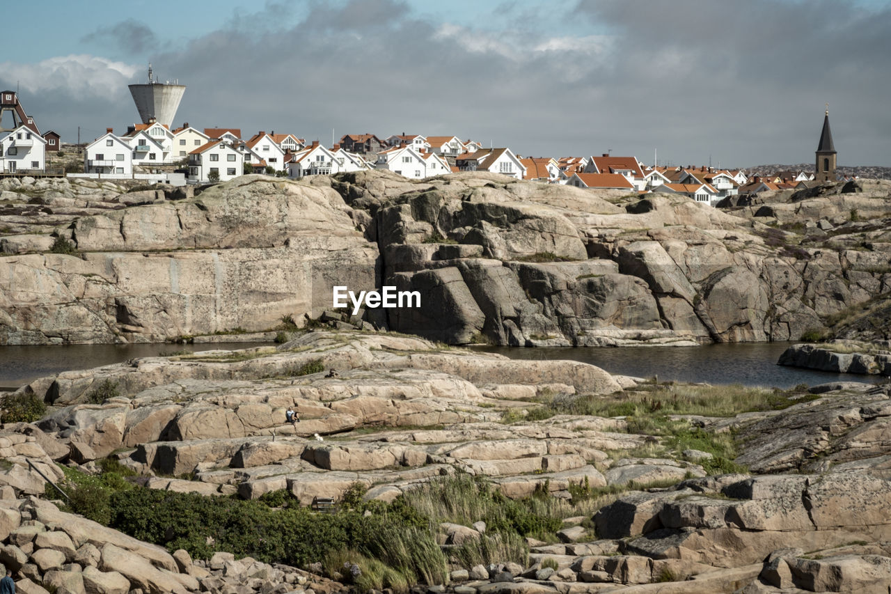 Cityscape on rock formation against cloudy sky
