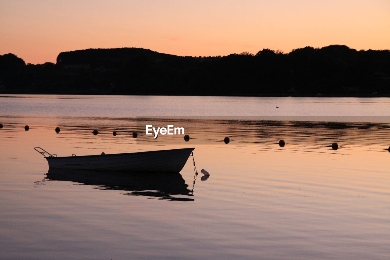 Silhouette boat in lake against sky during sunset