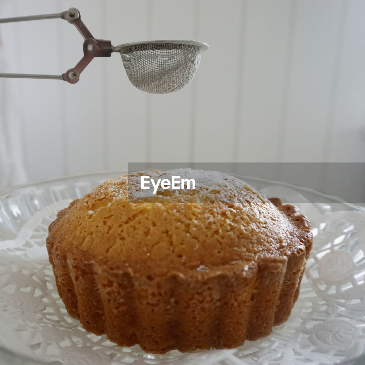 Close-up of strainer over cake on cakestand