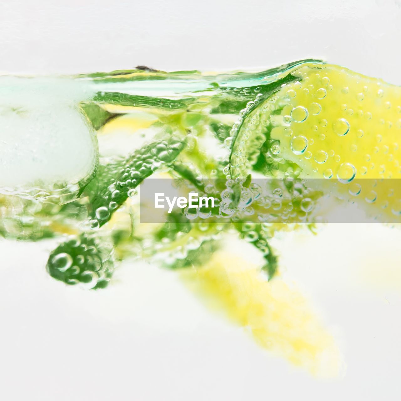 Close-up of herbs and lemon slices in liquid against white background