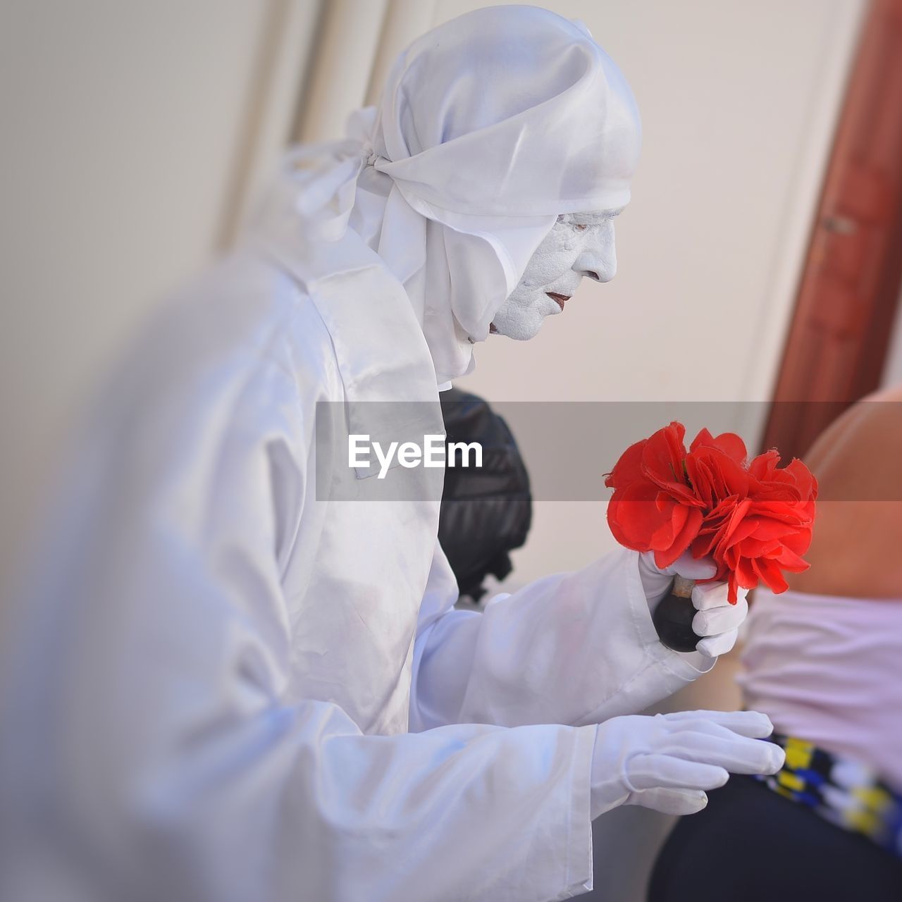 Close-up of woman in costume holding artificial red flower