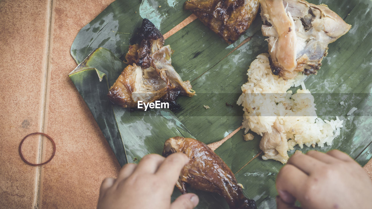 Cropped hands eating food on banana leaf