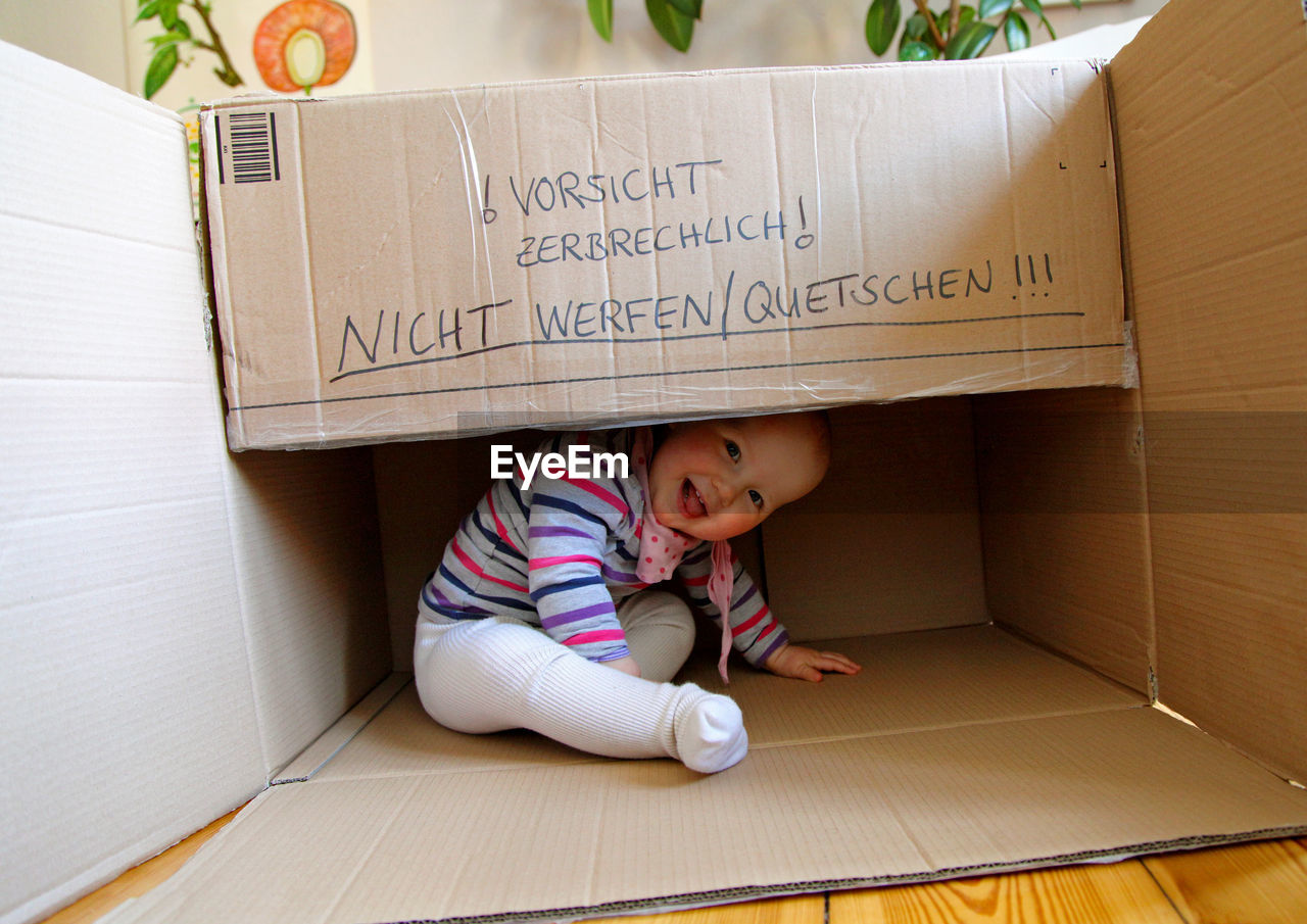 High angle view of cute girl sitting on floor at box