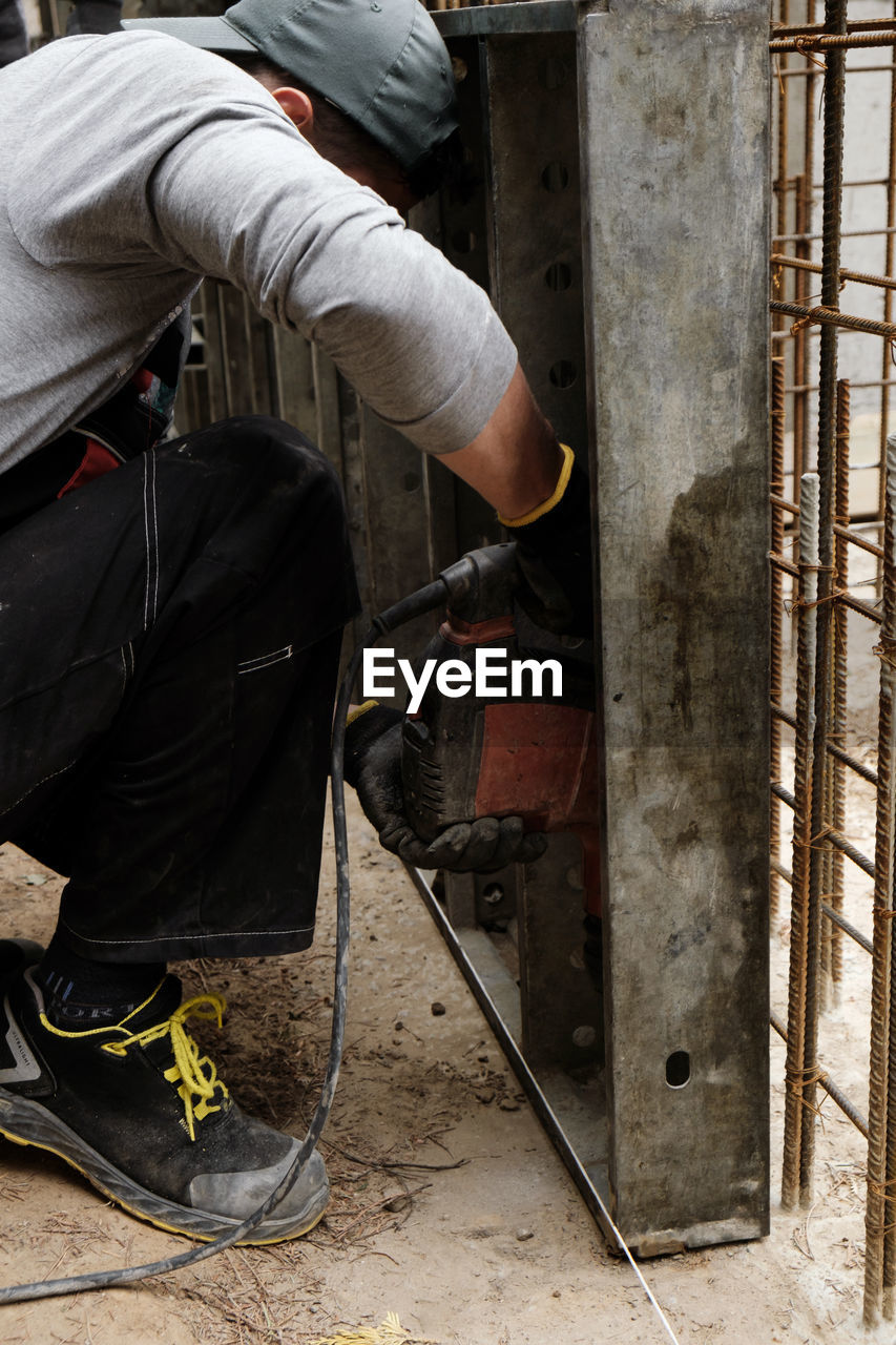 Builder with drill. man carpenter twists a screw into wooden plank with an electric screwdriver