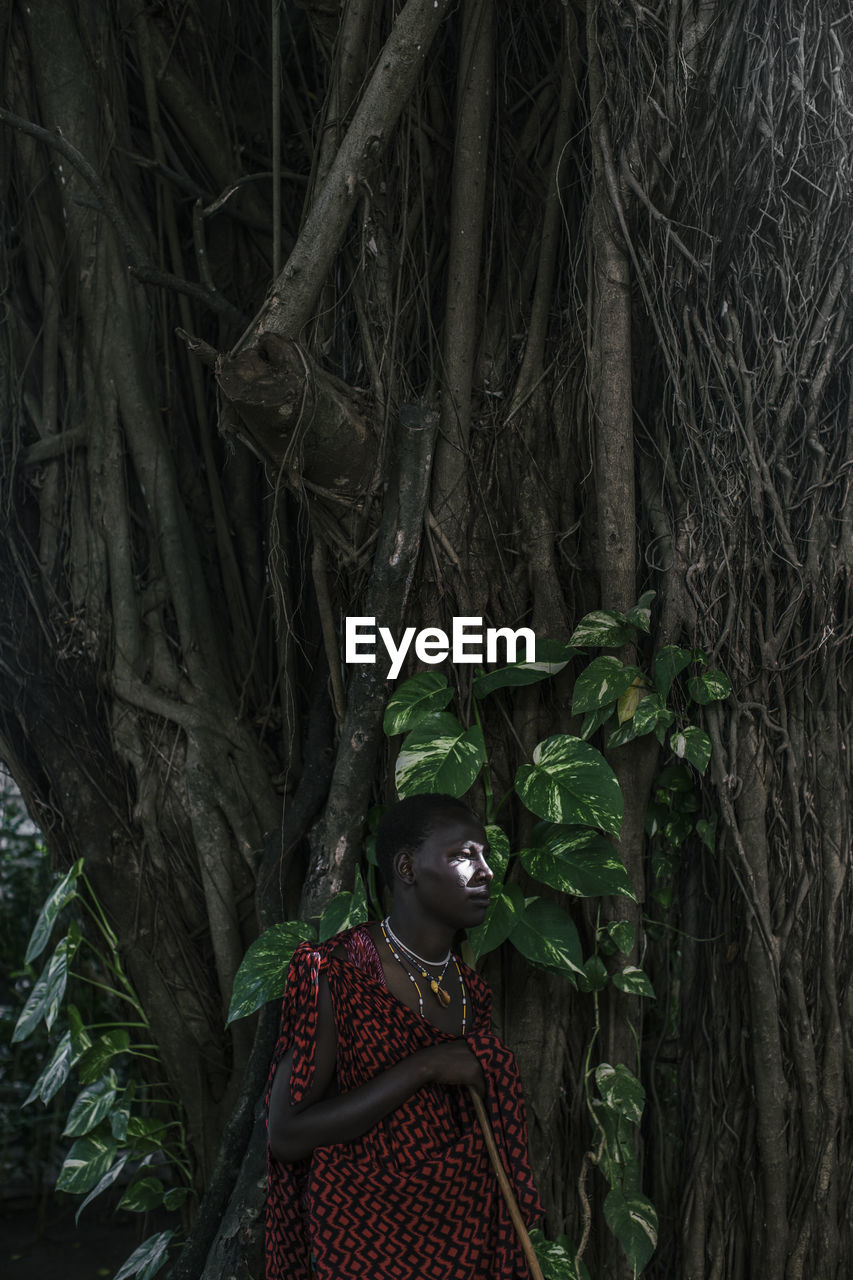 Maasai man in traditional clothes standing in the forest