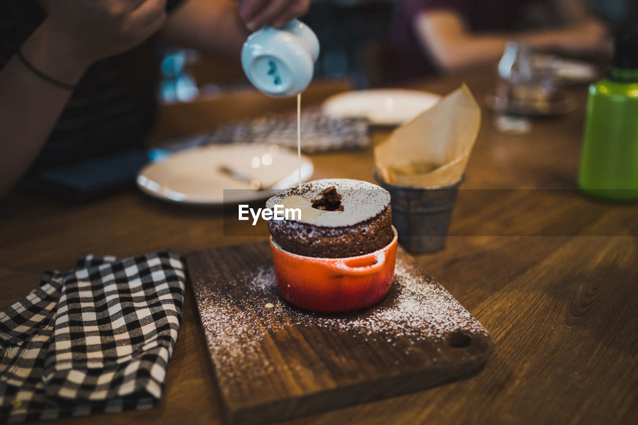 Cropped image of hand pouring syrup on desert