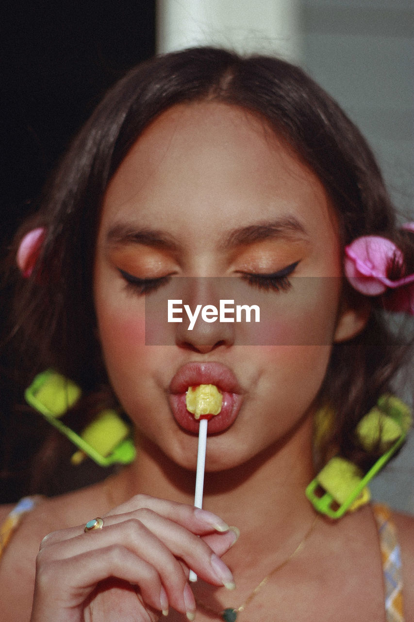 Close-up of young woman with eyes closed eating lollipop