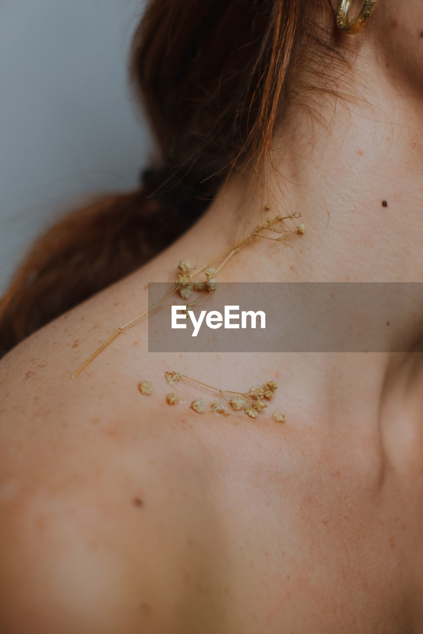 Close-up of woman with dried flowers on neck